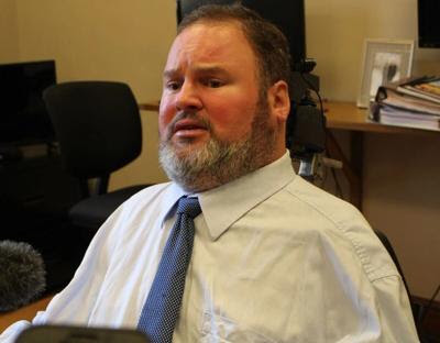 Steven Fletcher seated in an office wearing a white shirt and blue tie