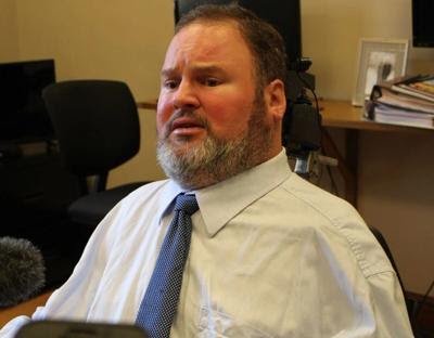 Steven Fletcher seated in an office wearing a white shirt and blue tie